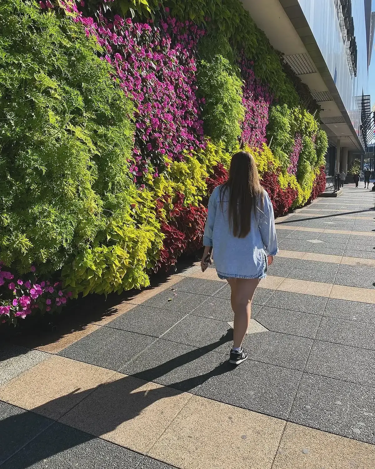 Sarah Martin walking past a living wall of flowering plants