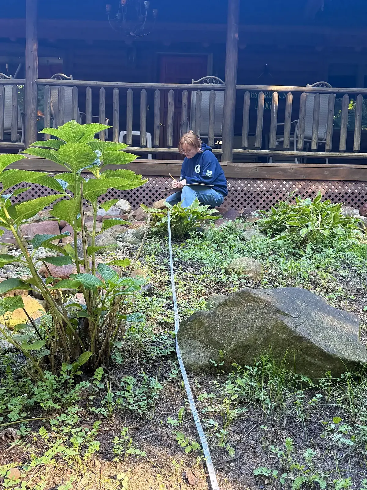 A gardener planting a sloped bed below a covered deck