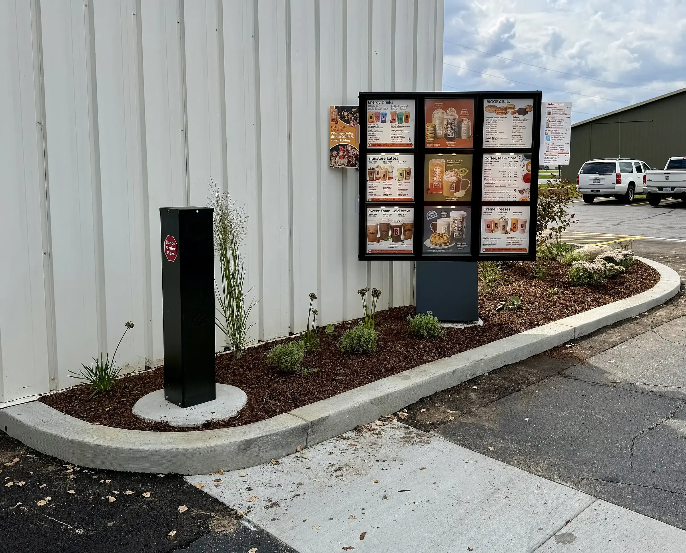 A new planting bed with mulch and young perennials beside a commercial building's sign