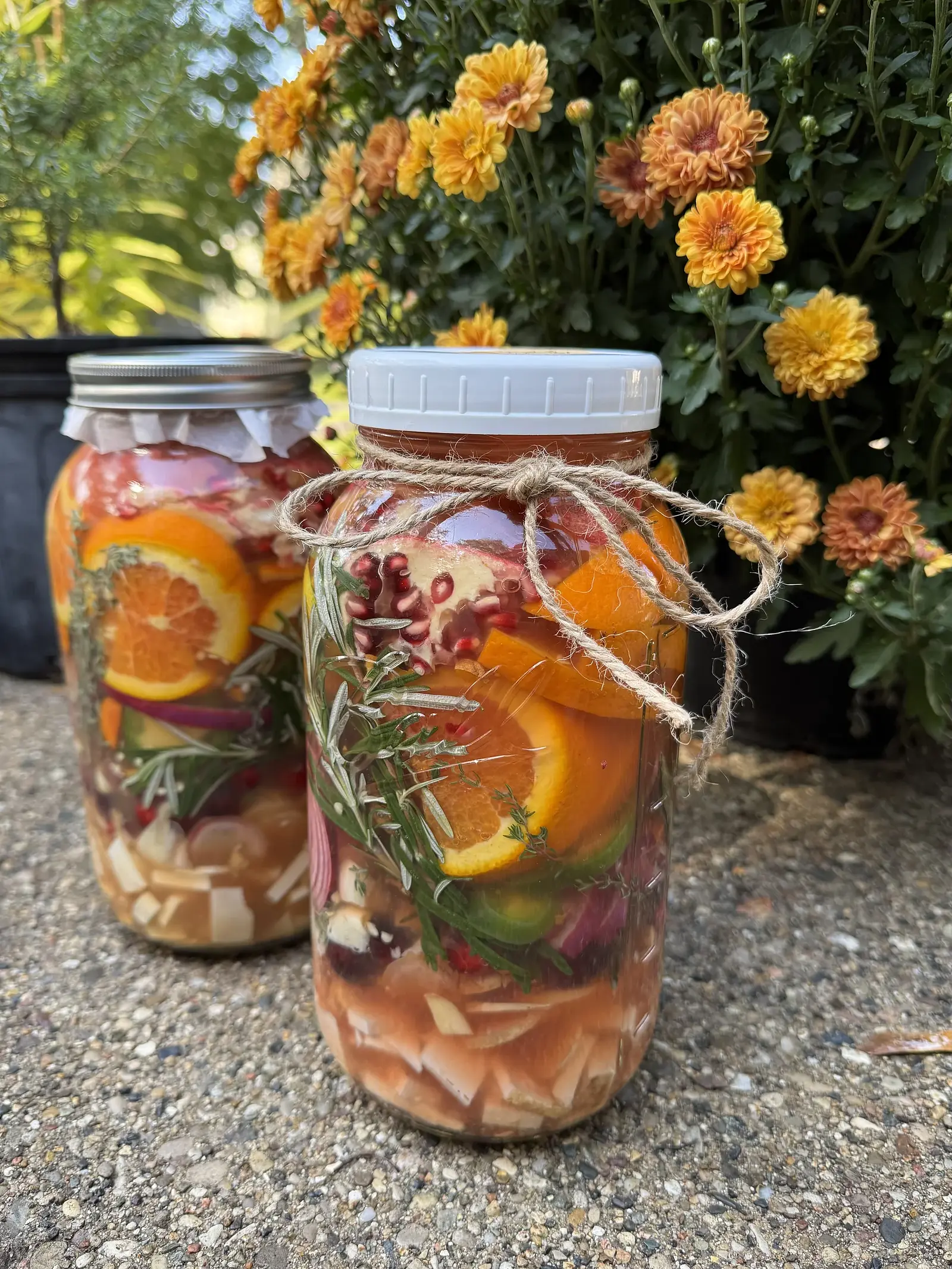Jars of herbal infusion with citrus beside orange marigolds